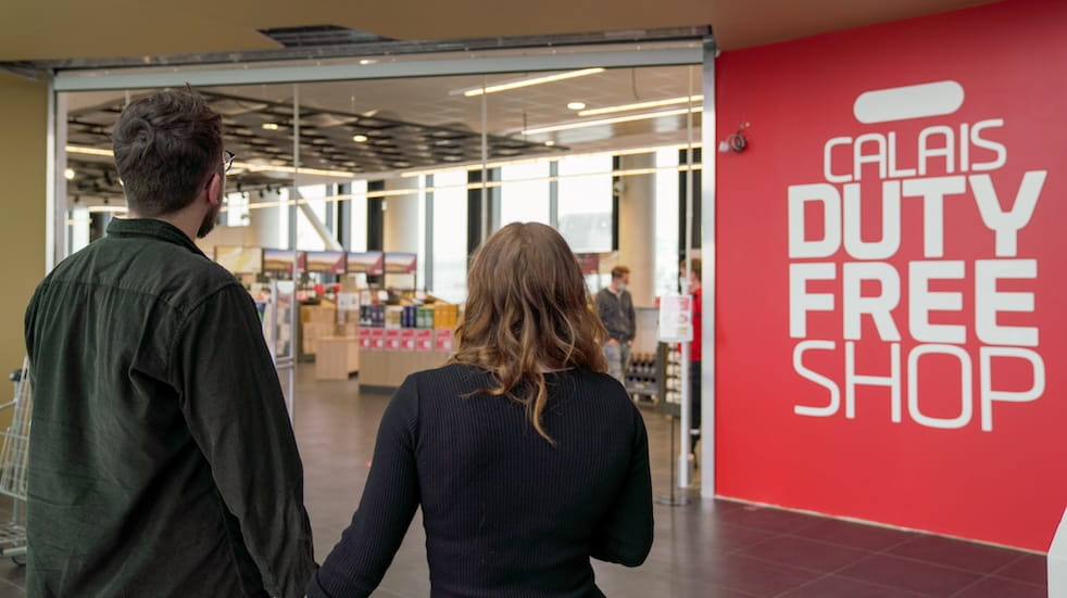 Couple from the back walking into Calais Duty Free Shop
